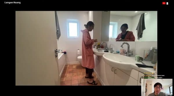 A video-call view of a performer reflected in a bathroom mirror.